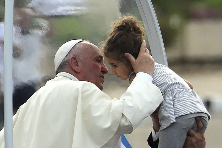 El Papa  besa a una niña a la que hiceron llegar al papamóvil. EFE