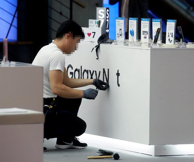 En la imagen, un empleado quitando las marca publicitaria de Galaxy Note 7 de la empresa Samsung Electronic en una tienda en Seúl (Corea del Sur). EFE/Archivo