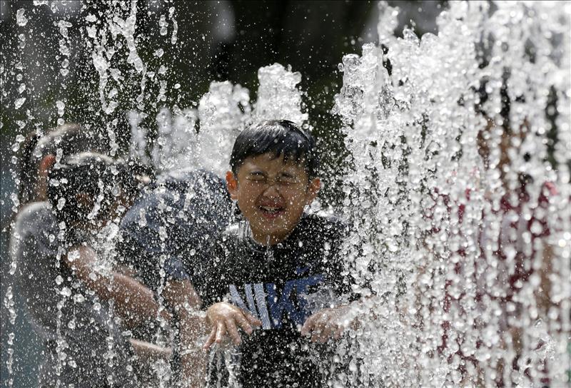 Varios niños juegan en una fuente para refrescarse en Tokio (Japón). EFE/Archivo
