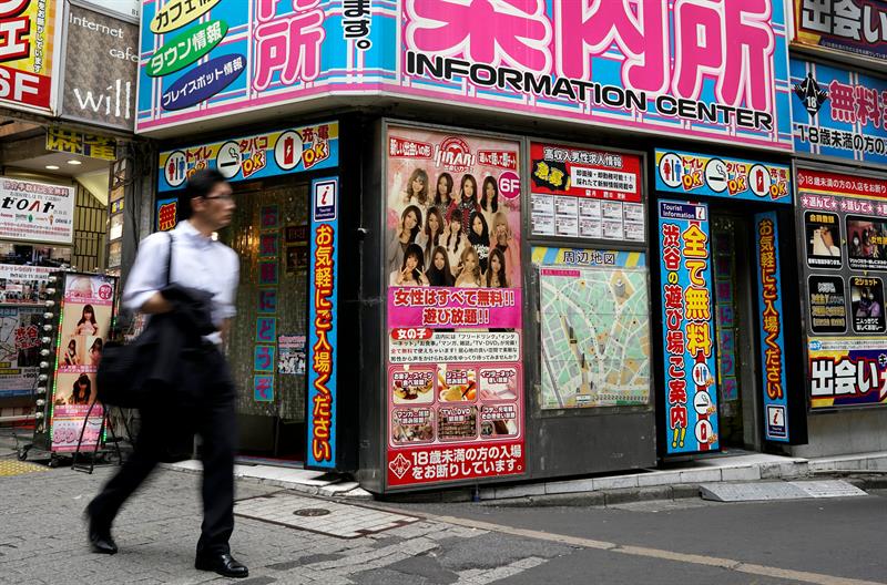 Un hombre pasa junto a un "centro de informacion" que ofrece asesoría sobre servicios orientados a adultos en el distrito de moda Shibuya en Tokio (Japón). EFE