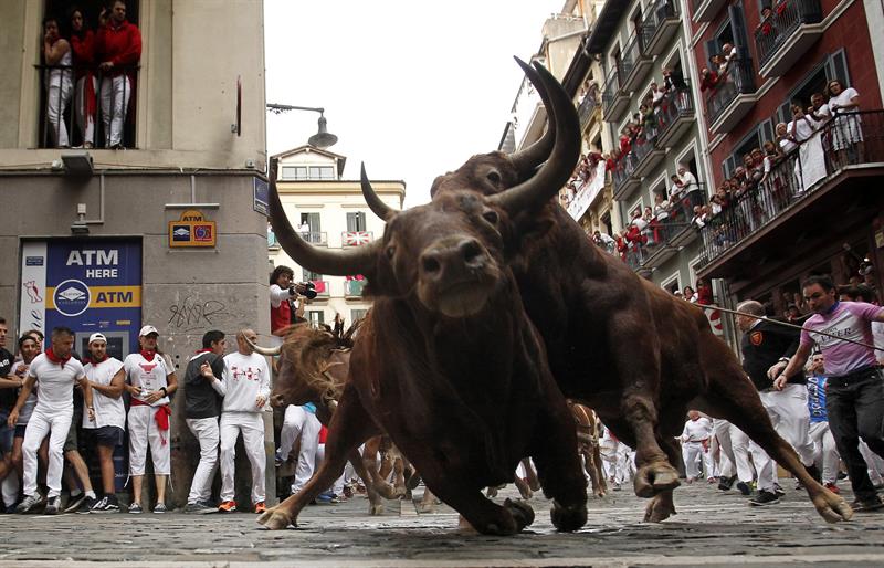 Dos toros de la ganadería de Jandilla resbalan en la curva de Mercaderes durante el quinto encierro de los Sanfermines 2017, que ha sido el más rápido hasta ahora. /  Foto: EFE