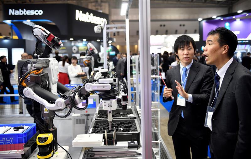 Un par de asistentes observan un robot industrial en el stand de THK en la Feria Internacional de la Robótica en Tokio (Japón) hoy, 29 de noviembre de 2017. Más de 600 compañías y organizaciones presentarán sus novedades hasta el 2 de diciembre. EFE