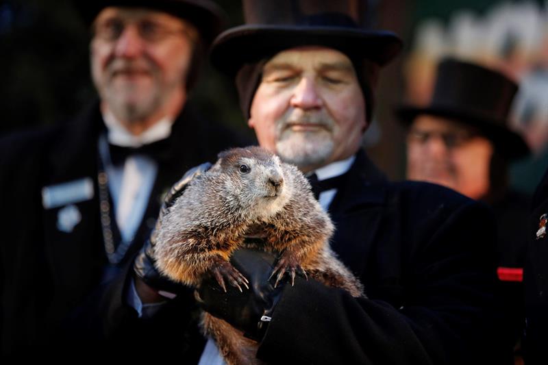 El cuidador John Grifiths (d), del Club de la Marmota, sostiene a la marmota Phil mientras el vicepresidente del club, Jeff Lundy (no fotografiado), lee la predicción de Phil para este año en Punxsutawney, Pensilvania, Estados Unidos. EFE