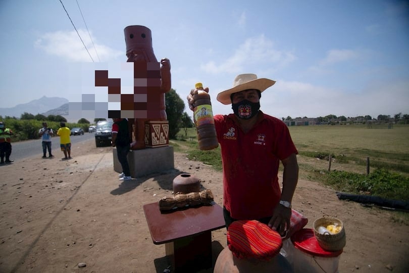 Un hombre vente productos junto a una estatua, hoy, en Moche (Perú). EFE