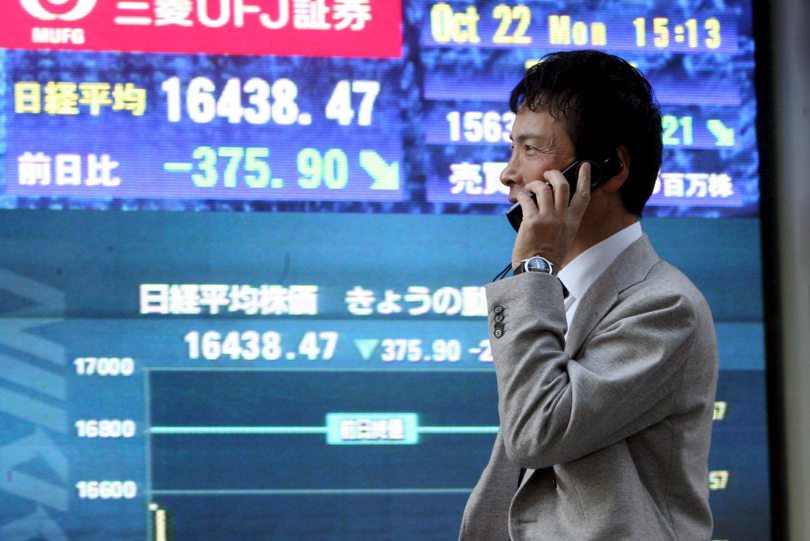 En la imagen de archivo, un hombre pasa delante de una pantalla que muestra el índice Nikkei de la Bolsa de Tokio. EFE