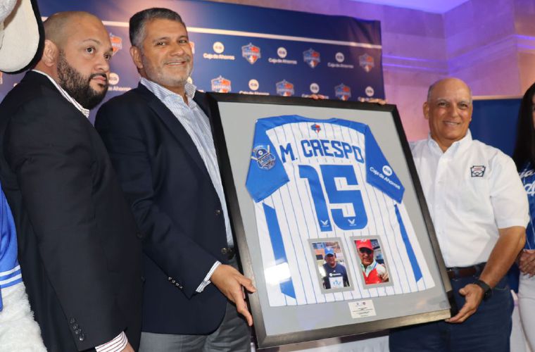 Martín Crespo (der.) recibe un obsequio en la conferencia en la que se oficializa la dedicatoria del Nacional de Béisbol Juvenil a su persona.