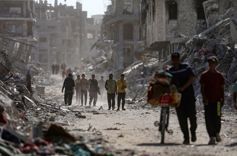 Palestinos caminan entre los escombros.