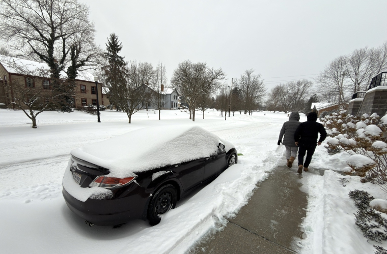 Dos personas caminan al lado de una calle afectada por la nieve este domingo en la ciudad de Hudson, Ohio.