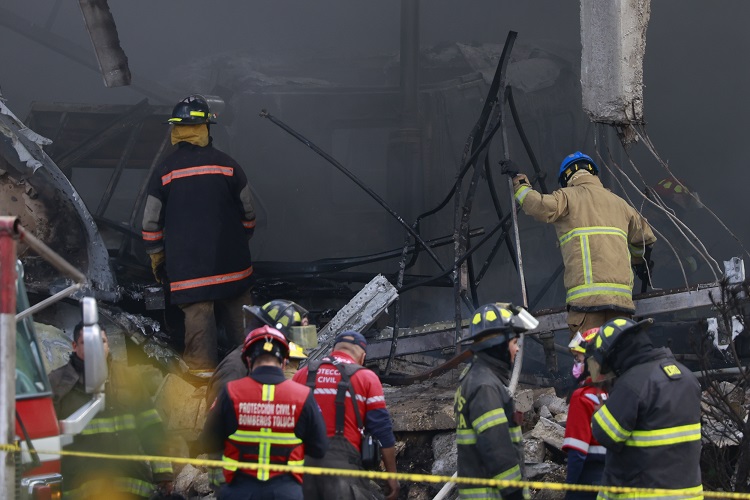 Integrantes de Protección Civil y bomberos trabajan en la bodega industrial donde cayó una avioneta Cessna Citation 650 este lunes, en el municipio de San Mateo Atenco, en el estado de México. Foto. EFE 