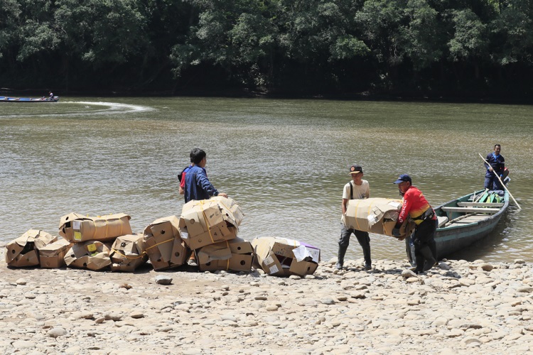 Personas descargan mercancía proveniente de Ecuador, en el cruce irregular sobre el río San Miguel que conecta a San Miguel (Colombia) con la zona rural de Lago Agrio (Ecuador). Foto. EFE