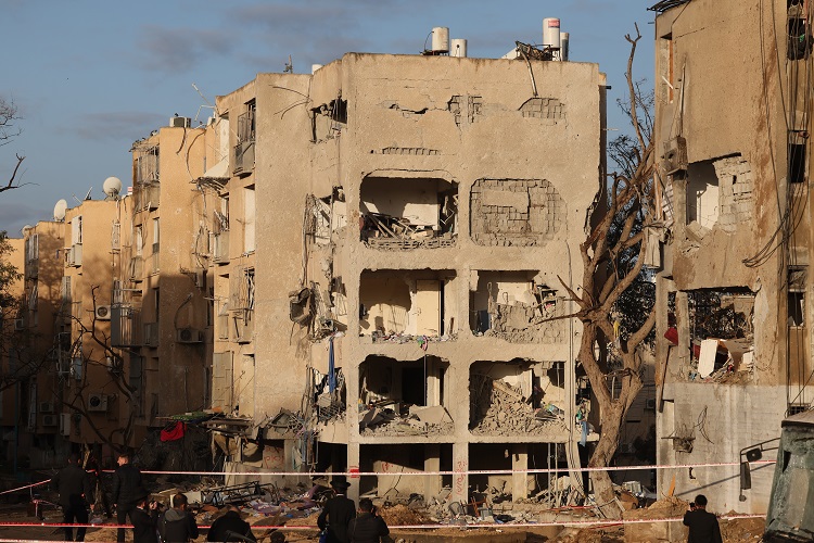 Varias personas observan la escena donde un misil iraní impacta directamente contra el territorio de Arad, Israel. Foto. EFE