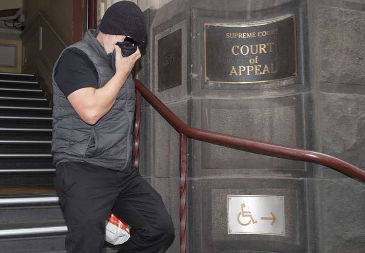 David Hingst, reclamante de acoso en el lugar de trabajo, se cubre la cara cuando abandona el Tribunal de Apelación en Melbourne, Australia, el viernes 29 de marzo de 2019. AP