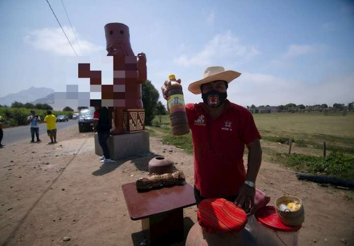 Un hombre vente productos junto a una estatua, hoy, en Moche (Perú). EFE