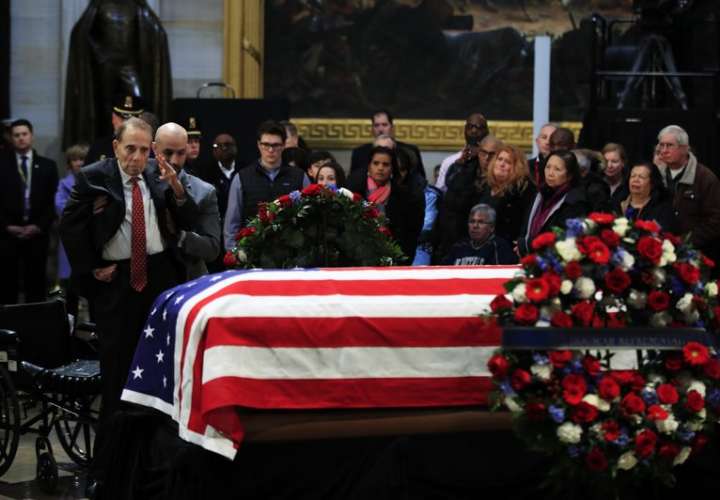 El exsenador Bob Dole saludó el ataúd cubierto con la bandera que contiene los restos del ex presidente George HW Bush se encuentra en estado en el Capitolio de los EE. UU. UU. en Washington. AP