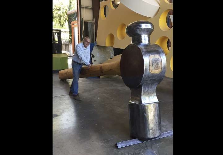 En esta foto de abril de 2017 lanzada por Doug Unkrey, el artista Unkrey posa para una foto con un gran martillo que creó en su estudio en Geyserville, California. AP