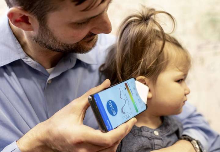 El Dr. Randall Bly usa una aplicación de teléfono y un embudo de papel para enfocar el sonido, para verificar si su hija tiene una infección en el oído, en la Escuela de Medicina de la Universidad de Washington en Seattle. AP