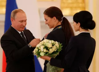 El mandatario de Rusia, Vladímir Putin (izq), impone una insignia a la campeona olímpica de esgrima, Sofia Velikaya (c). Foto EFE 