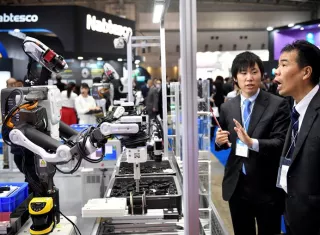 Un par de asistentes observan un robot industrial en el stand de THK en la Feria Internacional de la Robótica en Tokio (Japón) hoy, 29 de noviembre de 2017. Más de 600 compañías y organizaciones presentarán sus novedades hasta el 2 de diciembre. EFE