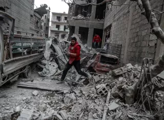 Un voluntario de Media Luna Roja corre tras un bombardeo en Duma, feudo rebelde de Guta Oriental (Siria). EFE
