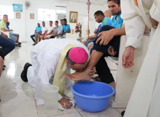Monseñor besa los pies a un privado de libertad. 