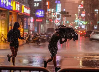 Un chico lucha con su paraguas bajo un fuerte chaparrón por el paso del tifón María en Taipei, Taiwán. EFE