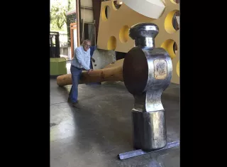 En esta foto de abril de 2017 lanzada por Doug Unkrey, el artista Unkrey posa para una foto con un gran martillo que creó en su estudio en Geyserville, California. AP