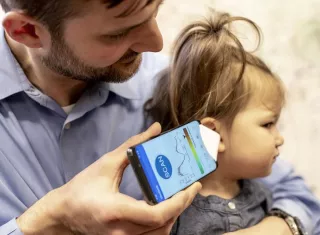 El Dr. Randall Bly usa una aplicación de teléfono y un embudo de papel para enfocar el sonido, para verificar si su hija tiene una infección en el oído, en la Escuela de Medicina de la Universidad de Washington en Seattle. AP