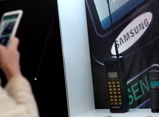 Un visitante toma imágenes de dos teléfonos de Samsung, el SH-100 de 1988 (i) y el SH-770 de 1994 (d) que están expuestos en el expositor de la firma corean durante la XIX edición del Mobile World Congress (MWC). EFE/Archivo