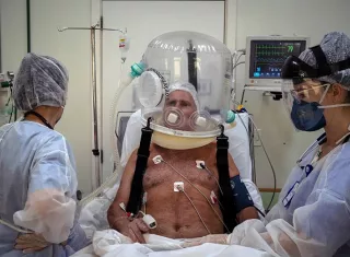 Trabajadores de la salud atienden con un casco burbuja a un paciente con la covid-19 hoy en la ciudad de Sao Leopoldo (Brasil). EF