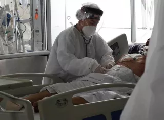 Una empleada de la salud atiende a un paciente en una unidad de cuidados intensivos para enfermos de covid-19. EFE