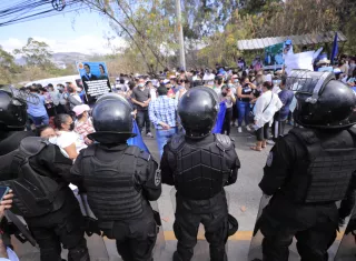 Miembros de la policía vigilan a simpatizantes del expresidente de Honduras Juan Orlando Hernández que se reúnen a las afueras de la Corte Suprema de Justicia. EFE