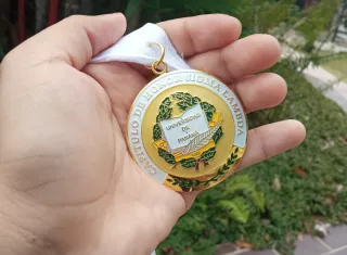 Luz Elleny Martínez Martínez, sostiene la Medalla Capítulo de Honor Sigma Lambda, la que al igual que su diploma, retiró por ventanilla en la Secretaría General de la UP. Foto: Cortesía.