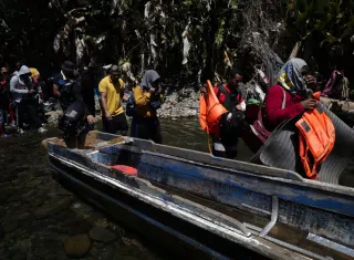 Personas migrantes esperan en la selva para ser trasladados en canoa desde la Quebrada León hasta a la comunidad de Bajo Chiquito. EFE