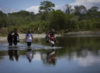 Personas migrantes cruzan el río Tuquesa, en Darién (Panamá), en una fotografía de archivo. EFE