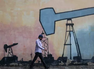 Un hombre pasa frente a un mural que muestra el proceso de extracción de petróleo frente a una sede de la estatal Petróleos de Venezuela S.A (Pdvsa). EFE