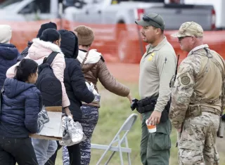 Un grupo de migrantes (i) que pasa junto a agentes de la Patrulla Fronteriza (c) y de la Guardia Nacional de Texas (d), en Shelby Park en Eagle Pass, Texas (EE.UU.). EFE / Archivo