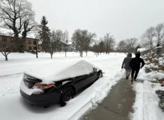Dos personas caminan al lado de una calle afectada por la nieve este domingo en la ciudad de Hudson, Ohio.