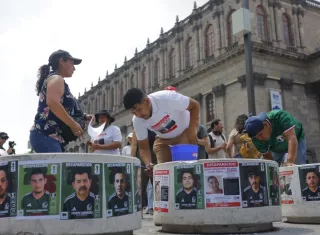 Personas pegando fichas de búsqueda de desaparecidos en el centro histórico de la ciudad de Guadalajara.