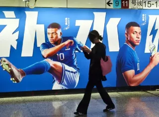 Una mujer camina frente a un cartel con publicidad de Kylian Mbappé en Shangái en junio de 2026.