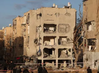 Varias personas observan la escena donde un misil iraní impacta directamente contra el territorio de Arad, Israel. Foto. EFE