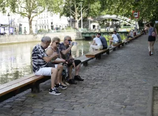 Varias personas descansan a orillas del Sena en París, luego de una de las madrugadas más calurosas. Foto. EFE