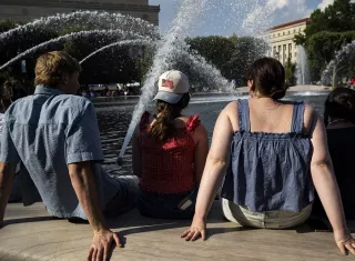 Personas se refrescan en la fuente del Jardín de Esculturas de la Galería Nacional de Arte, en el National Mall de Washington, DC (EE.UU.), durante temperaturas de calor extremo. Foto. EFE