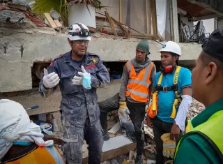 Un bombero asesora a mineros artesanales para trabajan en las ruinas ubicadas en Caraballeda/Venezuela. Foto. EFE
