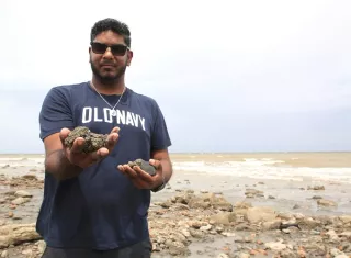 El estudiante de la Universidad de Trinidad y Tobago Joshua Jadoo mostrando fragmentos de piritas surgidos por los terremotos de Venezuela en Cedros. Foto. EFE