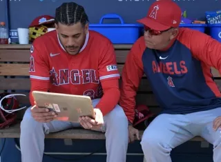 José Siri (i), de los Angelinos de Los Ángeles, observa un iPad en el dugout con el coach asistente del equipo, Jobel Jiménez, durante un partido contra los Dodgers de Los Ángeles, el 7 de junio de 2026. 