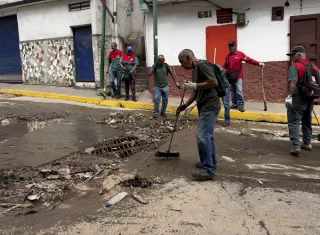 Un grupo de personas fue captado limpiando una calle, tras las fuertes lluvias de este fin de semana en Caracas (Venezuela). Foto. EFE