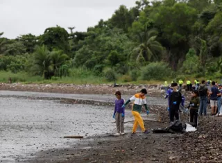 Personas recogen basura durante una jornada de limpieza de playas este sábado, en la desembocadura del Río Juan Díaz. Foto: EFE