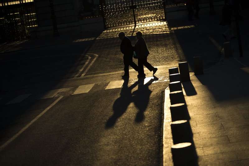 una pareja de ancianos camina por una calle cerca del Palacio Real de Madrid.  AP