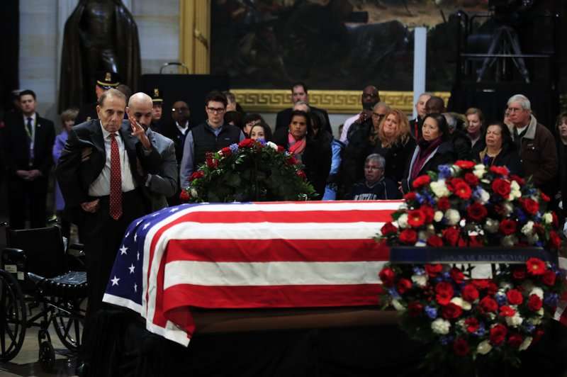 El exsenador Bob Dole saludó el ataúd cubierto con la bandera que contiene los restos del ex presidente George HW Bush se encuentra en estado en el Capitolio de los EE. UU. UU. en Washington. AP