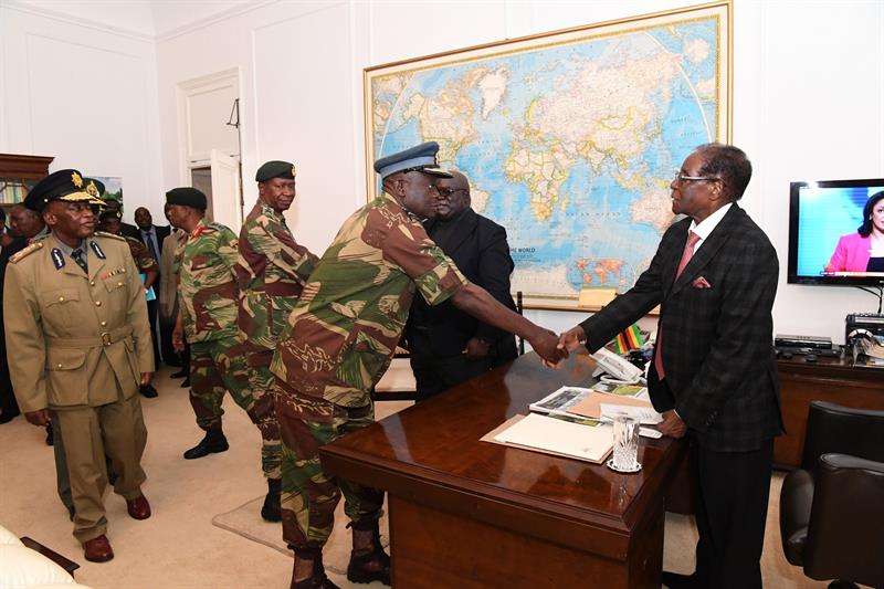 El presidente de Zimbabue, Robert Mugabe (d), saluda al comandante de las Fuerzas Aéreas del país, Perence Shiri (c), tras una reunión el domingo, con jefes militares y de seguridad en Harare. EFE/ The Herald FOTO CEDIDA/NO VENTAS